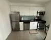 Kitchen featuring dark countertops, backsplash, appliances with stainless steel finishes, white cabinetry, and a sink