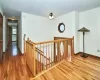 Hallway featuring baseboards, wood finished floors, and an upstairs landing