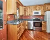 Kitchen with a sink, appliances with stainless steel finishes, dark countertops, dark wood finished floors, and glass insert cabinets