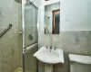 Full bath featuring a sink, a shower stall, toilet, and tile walls