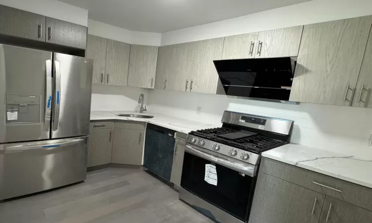 Kitchen with light wood-style flooring, a sink, appliances with stainless steel finishes, decorative backsplash, and light stone countertops