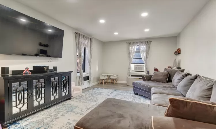 Living area featuring baseboards, light wood-type flooring, cooling unit, and recessed lighting