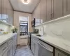 Kitchen featuring gray cabinetry, a sink, marble finish floor, ornamental molding, and appliances with stainless steel finishes