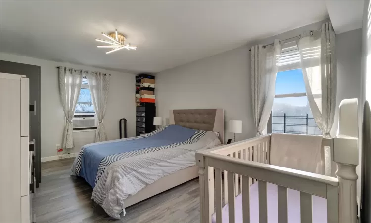 Bedroom featuring cooling unit, baseboards, and wood finished floors