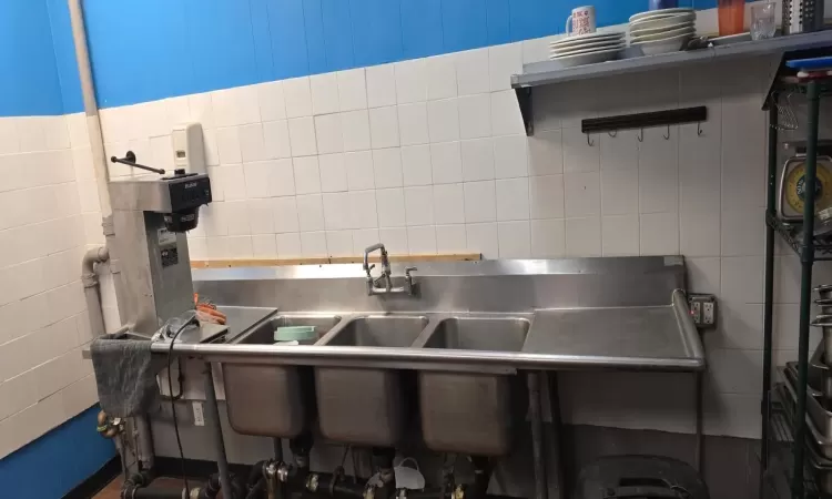 Kitchen with stainless steel countertops and tile walls