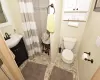 Bathroom with curtained shower, baseboards, vanity, and toilet