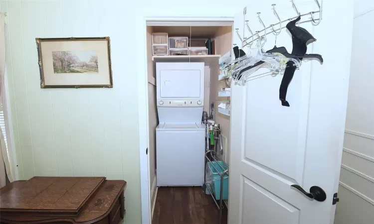 Laundry room featuring dark wood-style floors, stacked washer and dryer, and laundry area