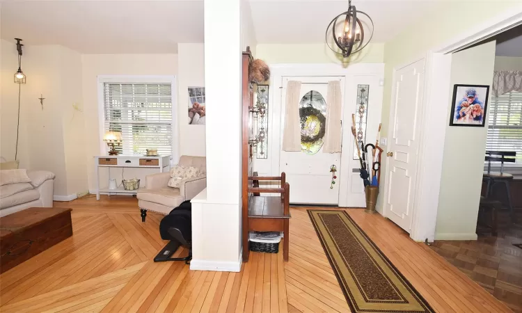 Foyer entrance featuring a healthy amount of sunlight, a notable chandelier, and wood finished floors