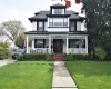 View of front facade featuring a shingled roof, a front lawn, a porch, and stucco siding