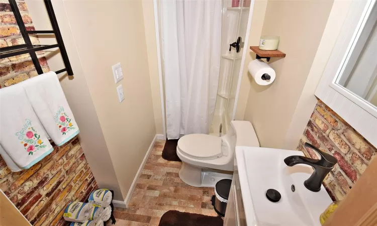 Bathroom featuring toilet, curtained shower, baseboards, and a sink