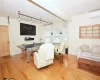 Living area with an AC wall unit, wood finished floors, and baseboards