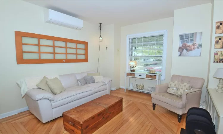 Living room featuring parquet flooring, baseboards, and a wall mounted AC