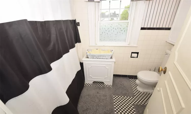 Full bath with tile patterned flooring, tile walls, and toilet