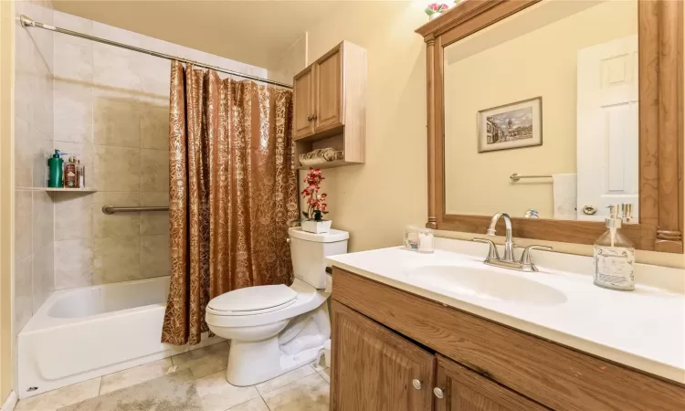 Bathroom featuring vanity, shower / bath combination with curtain, toilet, and tile patterned floors