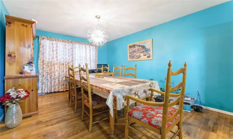 Dining area featuring a chandelier, wood finished floors, and baseboards