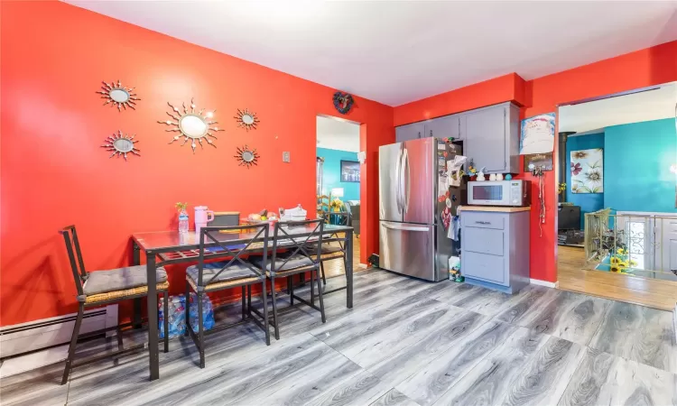 Dining space with a baseboard heating unit and wood finished floors