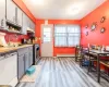 Kitchen with a baseboard heating unit, white dishwasher, a sink, gas range, and under cabinet range hood