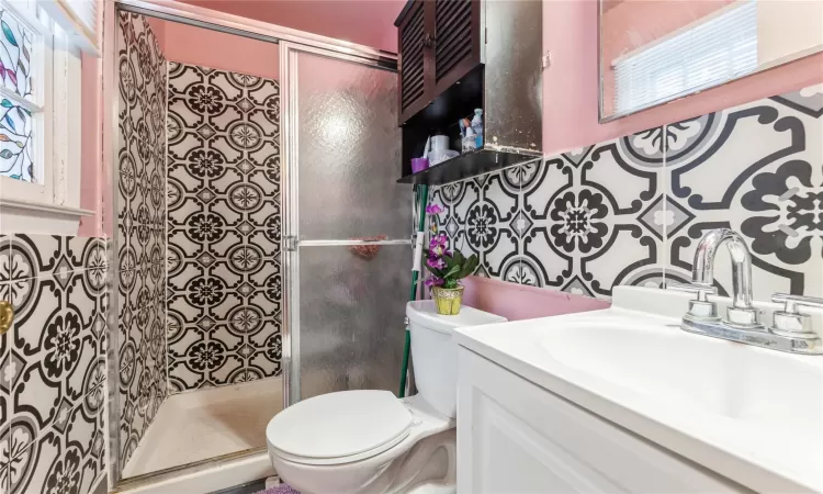 Bathroom featuring vanity, toilet, and a shower stall