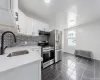 Kitchen with under cabinet range hood, stainless steel appliances, a sink, white cabinetry, and radiator