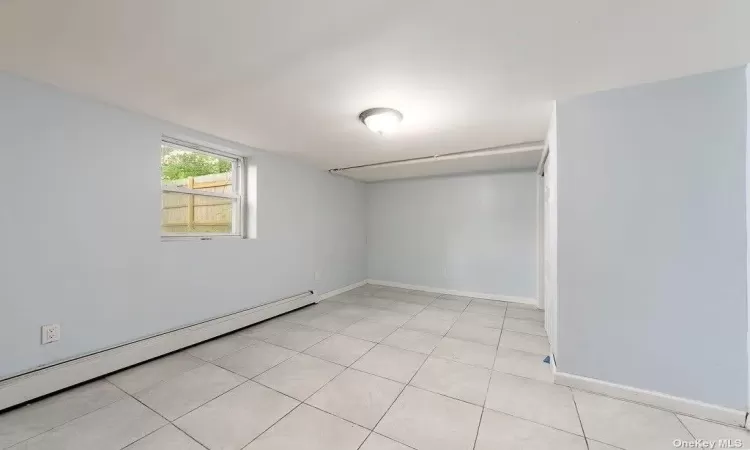 Spare room featuring baseboards, baseboard heating, and light tile patterned flooring