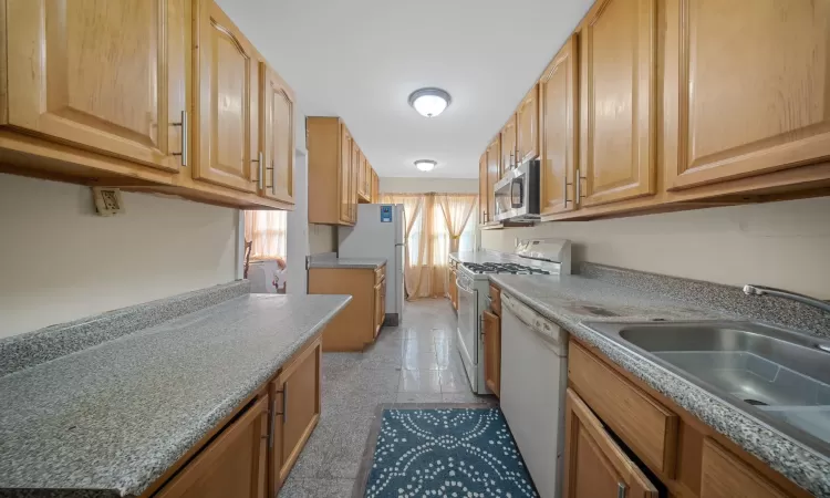 Kitchen featuring sink, white appliances, and light brown cabinetry