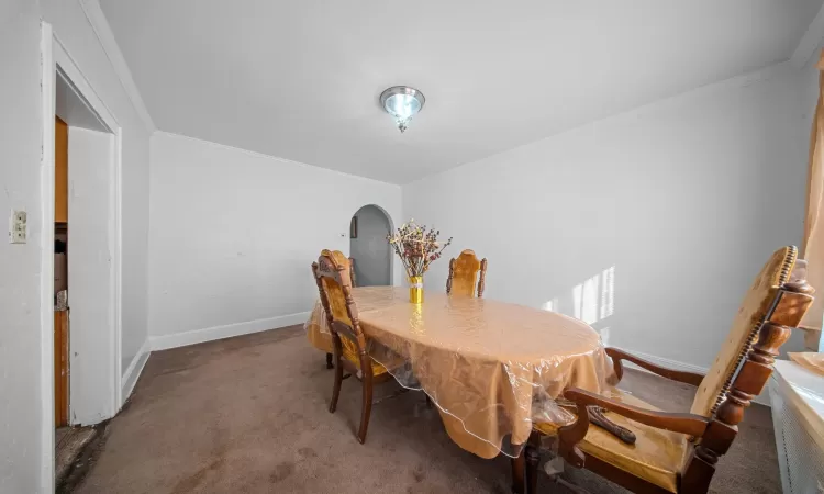 Carpeted dining area featuring crown molding