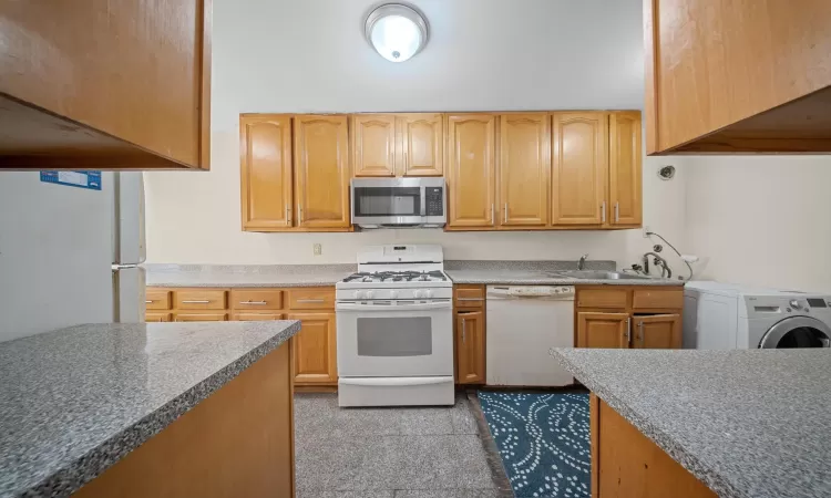 Kitchen featuring sink, washer / clothes dryer, and white appliances