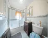 Full bathroom featuring toilet, radiator heating unit, tile walls, combined bath / shower with glass door, and tile patterned floors