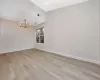 Spare room with light hardwood / wood-style flooring and a notable chandelier