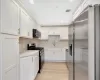 Kitchen with white cabinetry, sink, tasteful backsplash, light hardwood / wood-style flooring, and appliances with stainless steel finishes