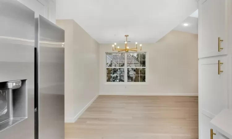 Unfurnished dining area with a notable chandelier and light hardwood / wood-style flooring