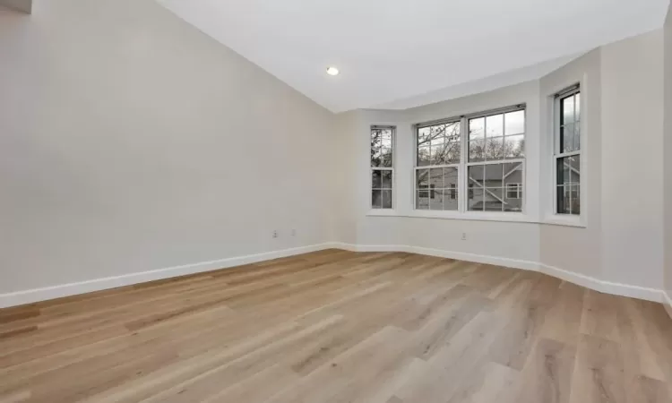 Unfurnished room featuring light hardwood / wood-style floors and lofted ceiling