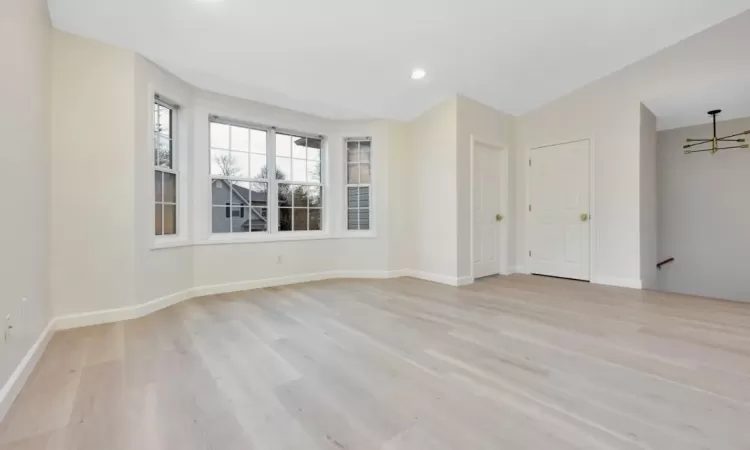 Unfurnished room with vaulted ceiling, light wood-type flooring, and an inviting chandelier