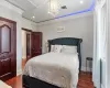 Bedroom featuring attic access, visible vents, wood finished floors, and ornamental molding