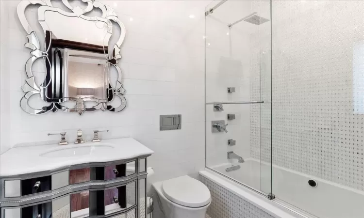 Full bath featuring toilet, tiled shower / bath, tile walls, and vanity