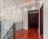 Hallway featuring dark wood-style floors, crown molding, an upstairs landing, a chandelier, and recessed lighting