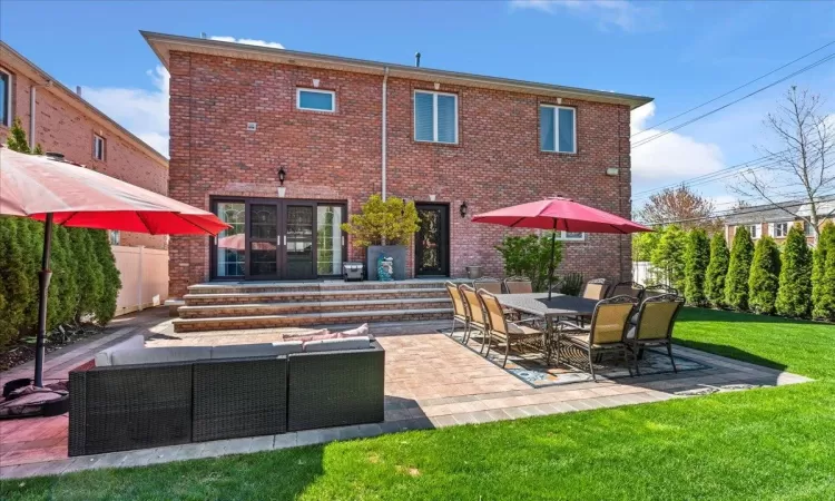 Rear view of house with brick siding, a lawn, a patio, and an outdoor hangout area