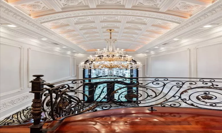 Corridor featuring an ornate ceiling, crown molding, a notable chandelier, a decorative wall, and vaulted ceiling