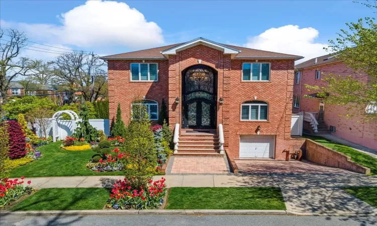 View of front of home with a garage, brick siding, fence, driveway, and french doors