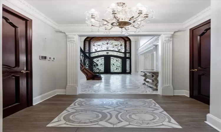 Entryway with an inviting chandelier, french doors, crown molding, and wood finished floors