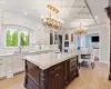 Kitchen with an inviting chandelier, glass insert cabinets, white cabinets, and a sink