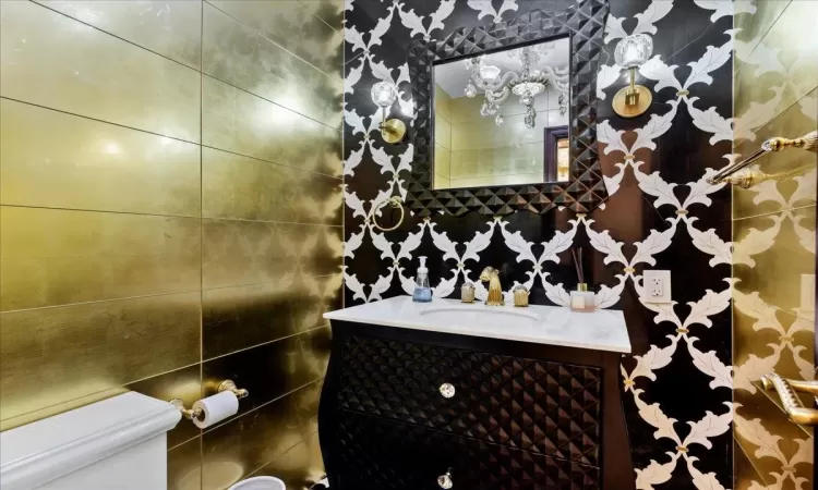 Bathroom featuring tile walls, vanity, and toilet