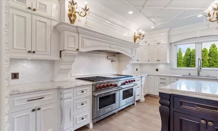 Kitchen featuring range with two ovens, a sink, white cabinets, light wood finished floors, and glass insert cabinets