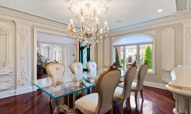 Dining room featuring a notable chandelier, crown molding, dark wood finished floors, and baseboards