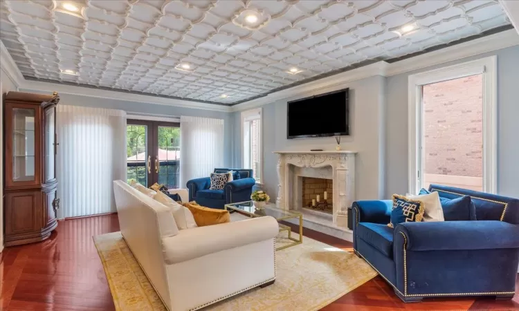 Living room with french doors, crown molding, a premium fireplace, and wood finished floors