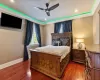 Bedroom with wallpapered walls, baseboards, wood finished floors, and ornamental molding