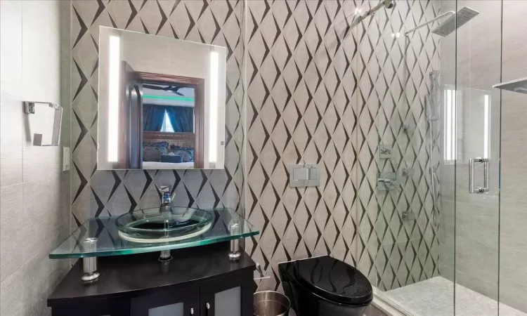 Bathroom with toilet, vanity, tile walls, tasteful backsplash, and a stall shower