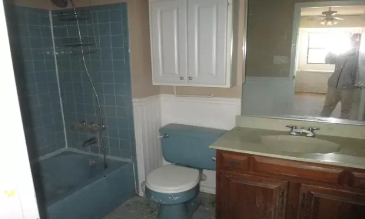 Full bath featuring tile patterned flooring, toilet, a wainscoted wall, vanity, and  shower combination