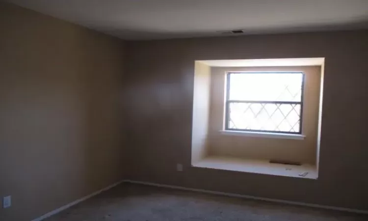 Carpeted empty room featuring visible vents and baseboards