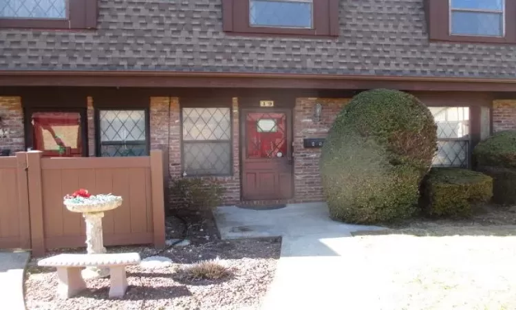 Entrance to property with a shingled roof, mansard roof, and brick siding